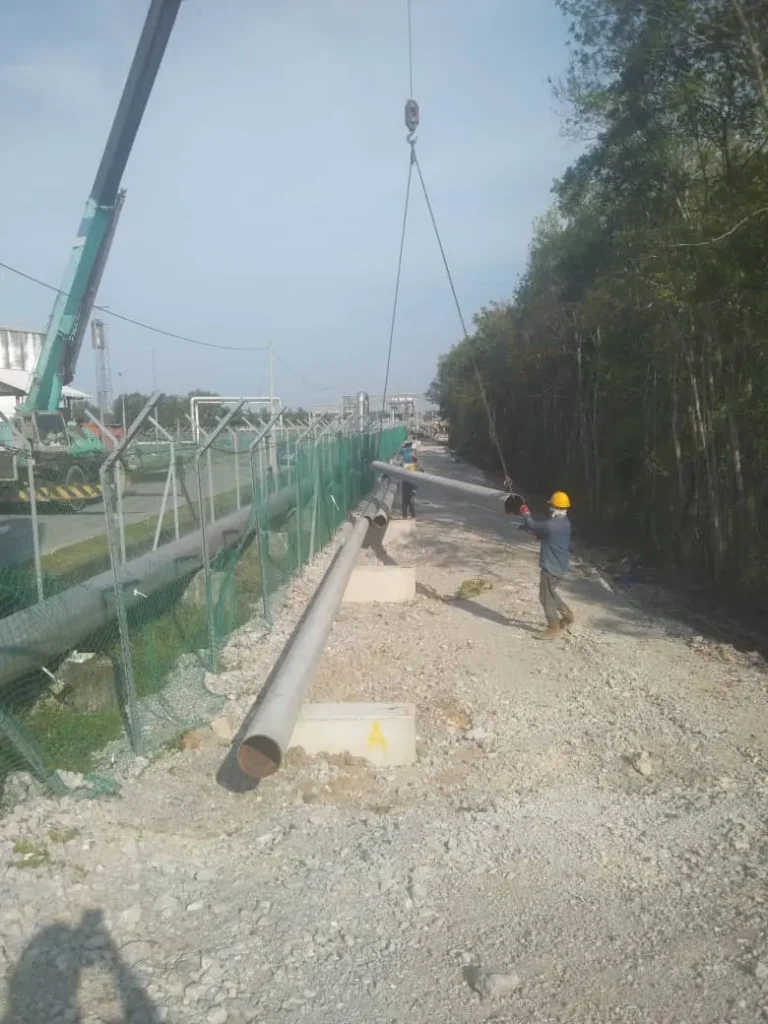 Piping supervisor overseeing pipe lifting operation for OSBL piping installation